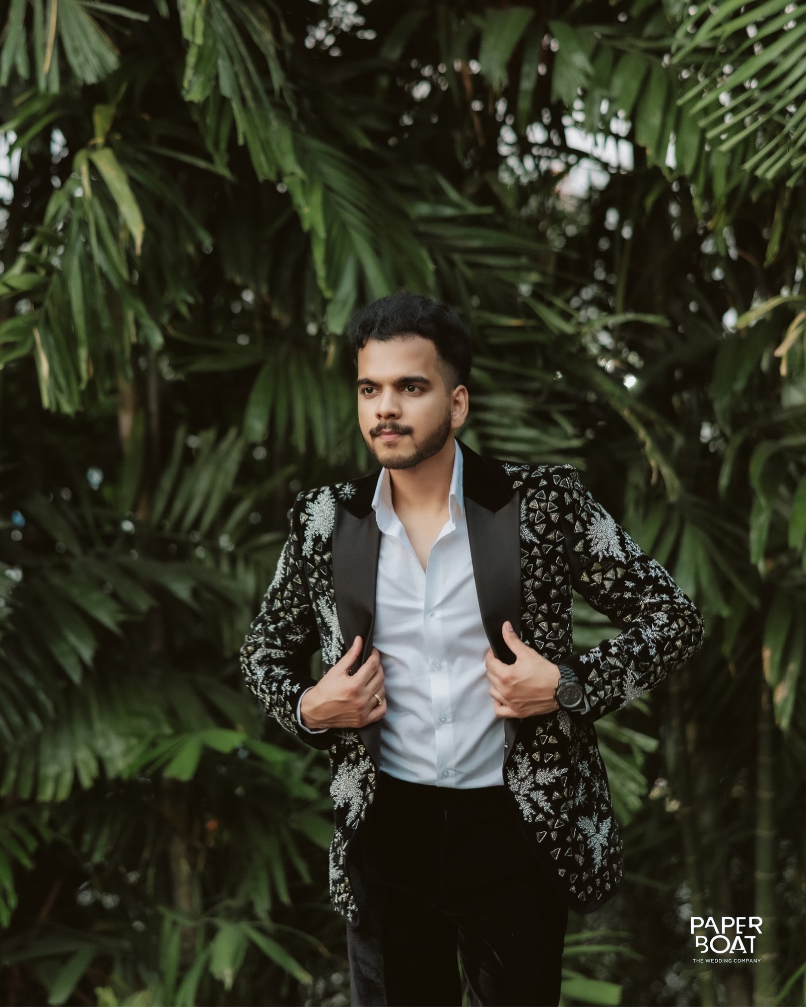 A groom standing against tropical greenery