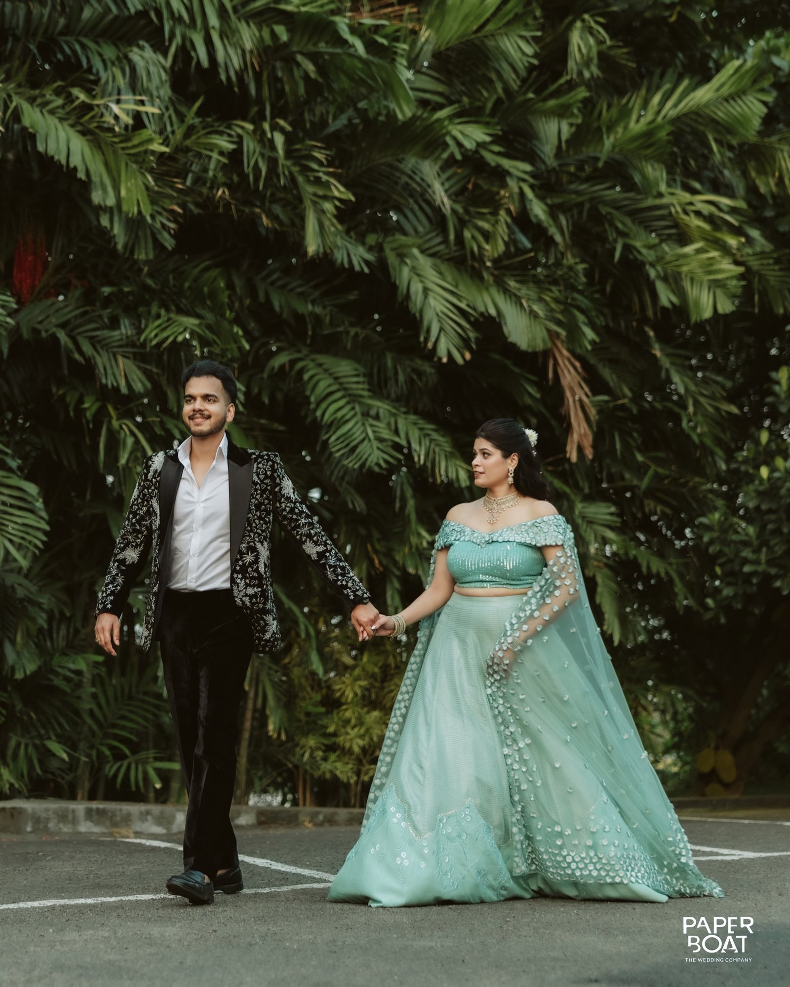 A couple walking hand in hand through lush greenery