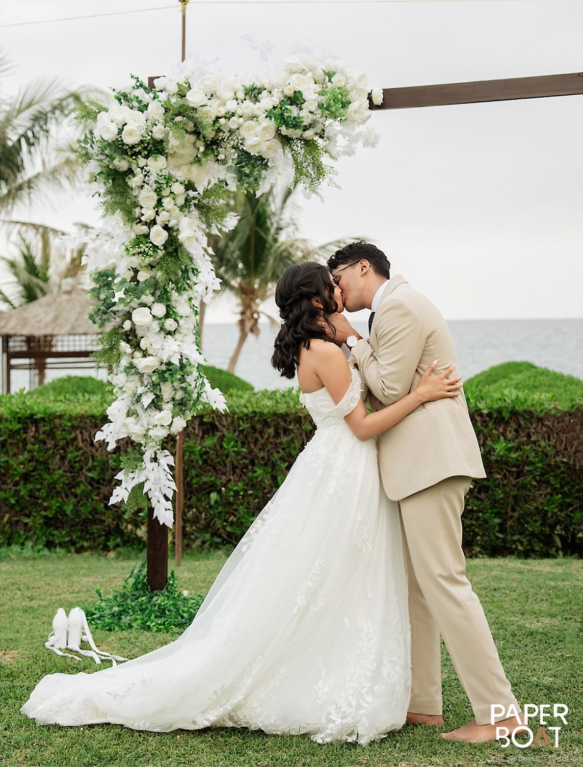 A newlywed couple kissing beneath a floral arch